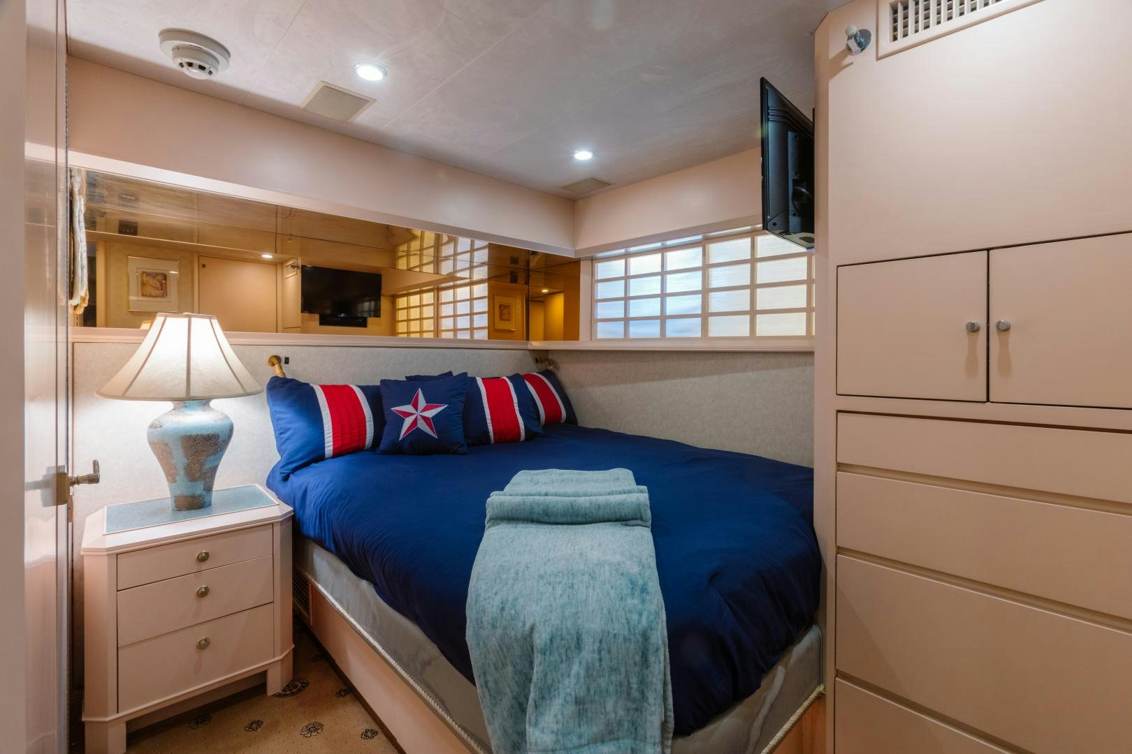 a bedroom with a blue bed and white cabinets aboard LORI LYNN Yacht for Sale