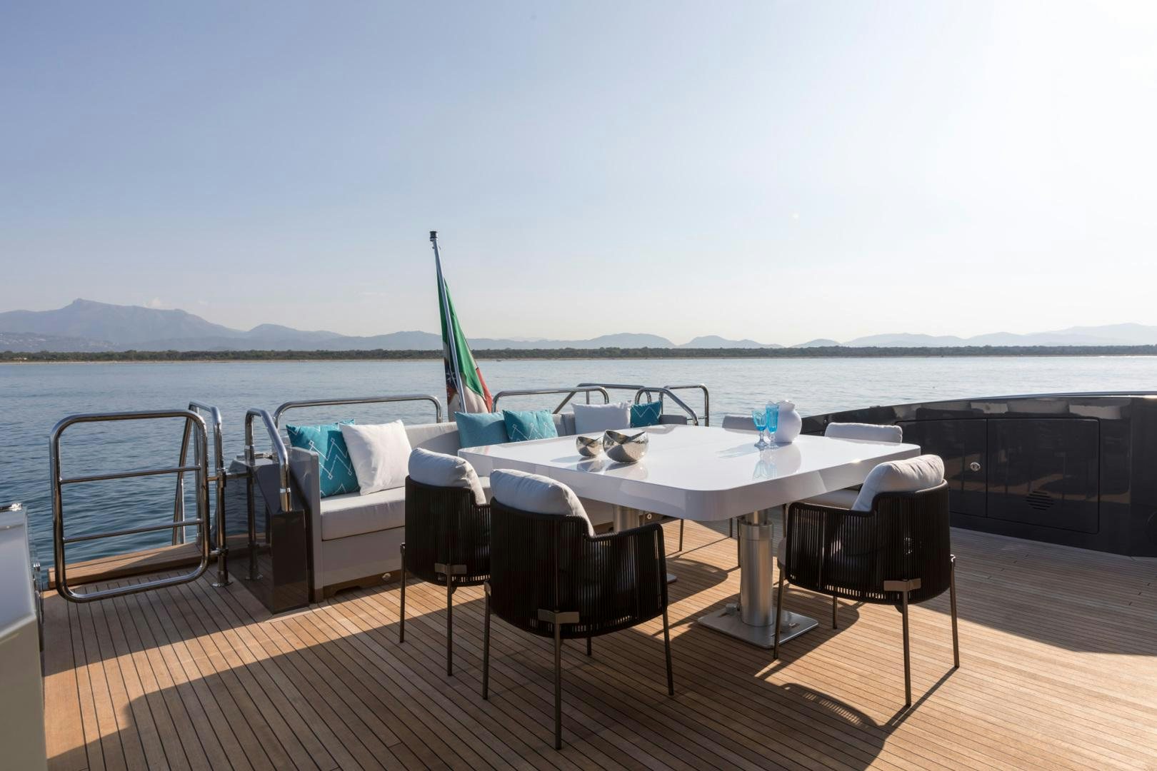 a table with chairs on a deck overlooking a body of water aboard NANA I Yacht for Sale