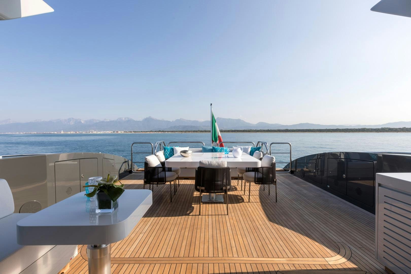 a deck with a table and chairs on it and a body of water in the background aboard NANA I Yacht for Sale
