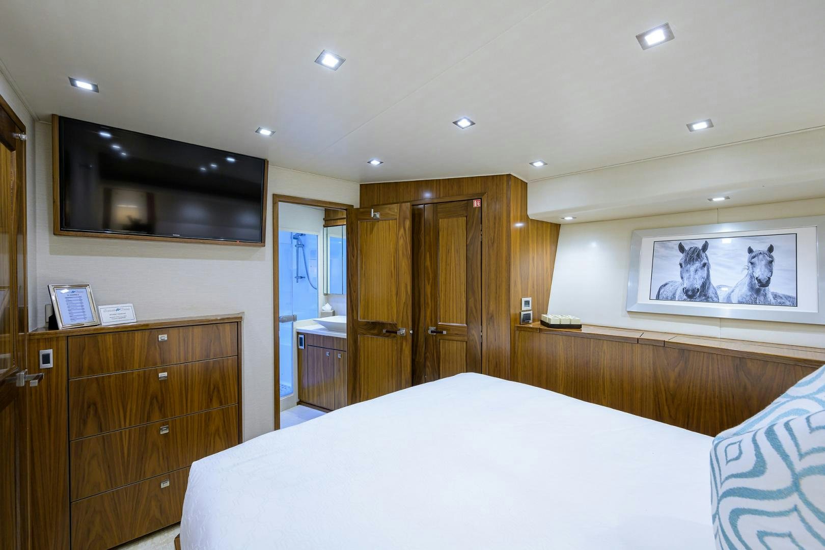 a bedroom with a large television and wood cabinets aboard PASTIME Yacht for Sale