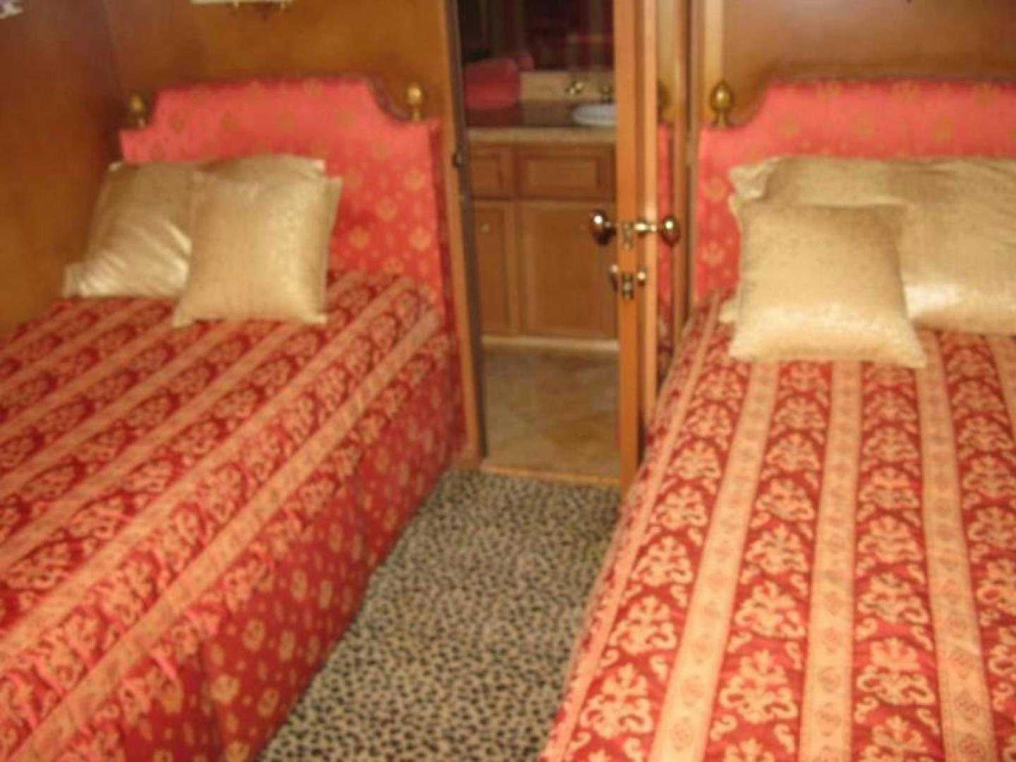a bedroom with red bedspread and a red and white rug aboard TRUE NORTH Yacht for Sale
