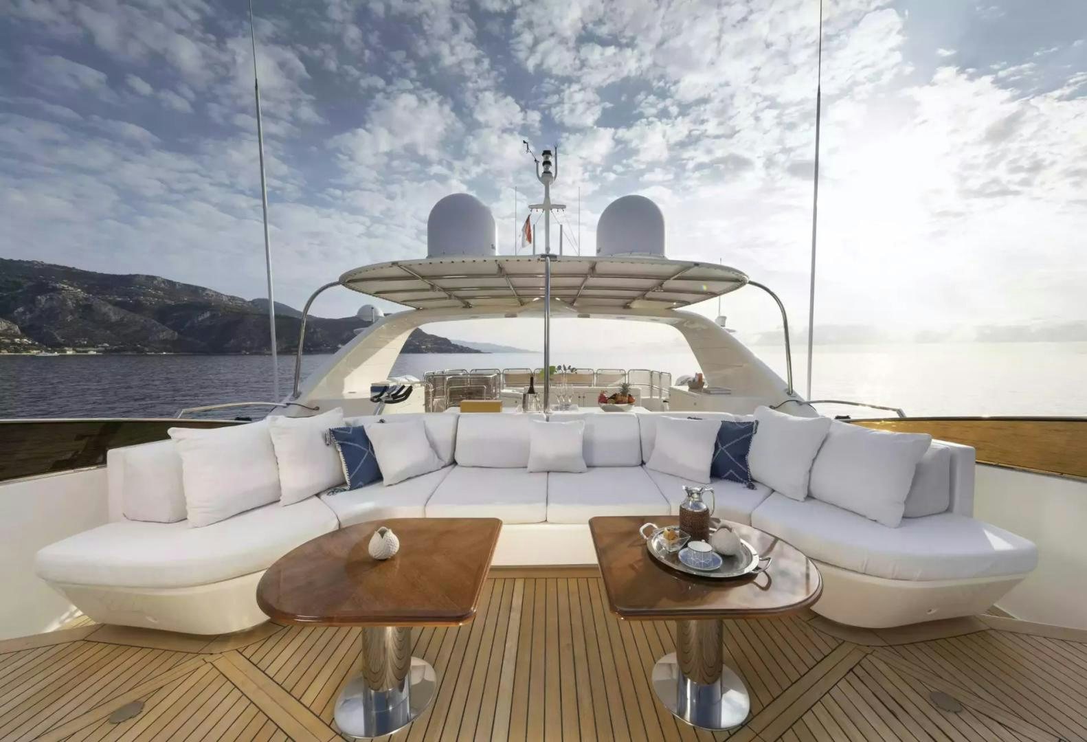 a white couch with a table and chairs in front of a large body of water aboard SOHO Yacht for Sale