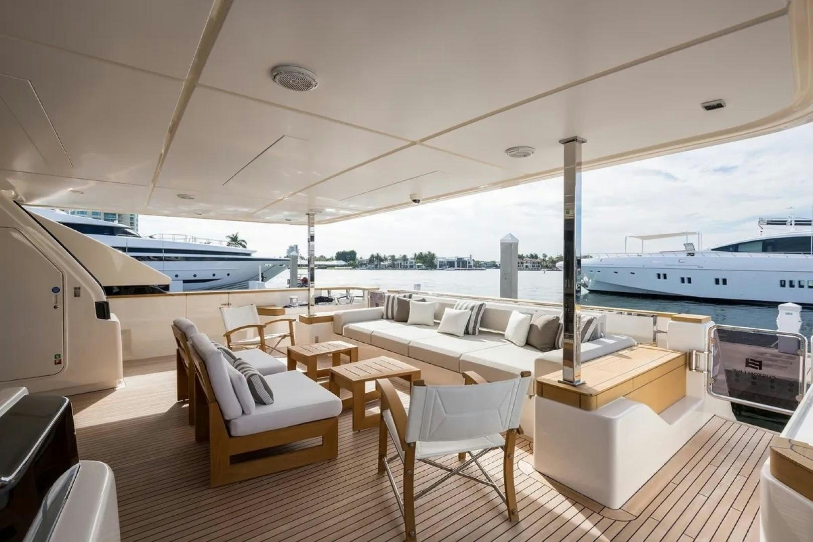 a room with a table chairs and a large boat in the background aboard GIOIA Yacht for Sale