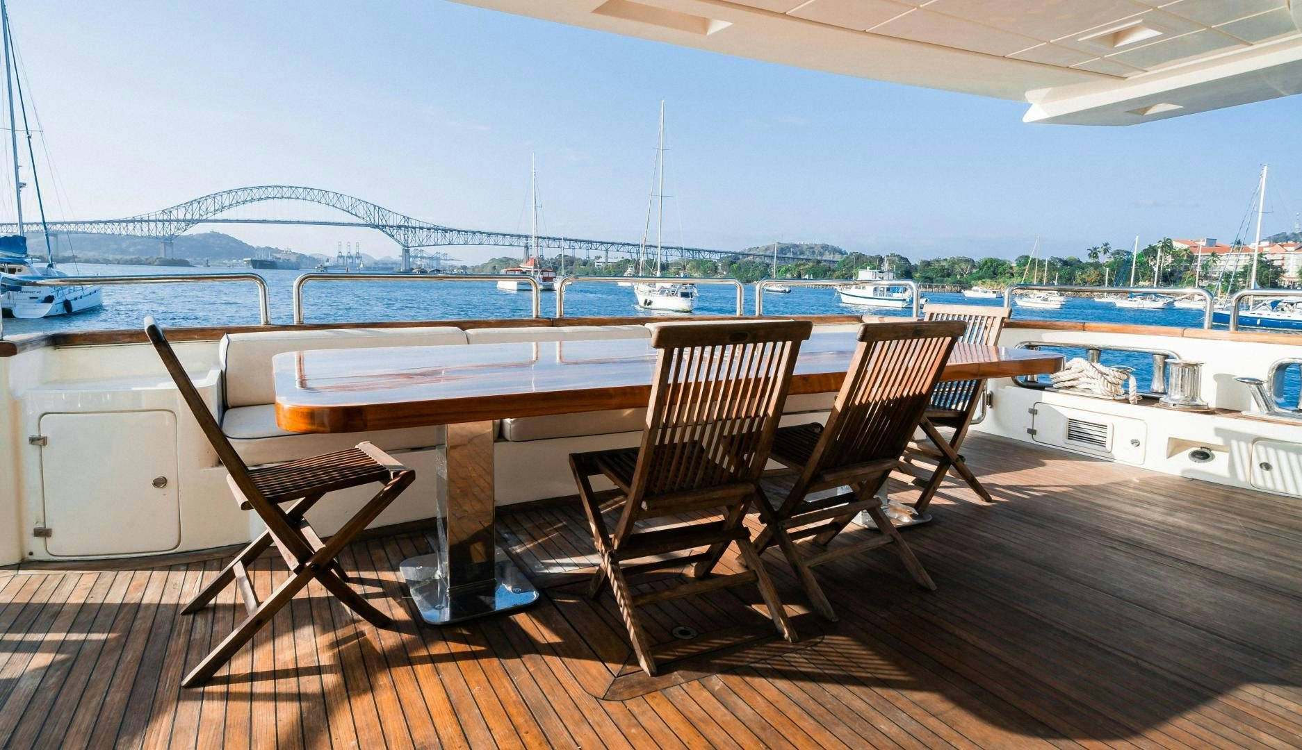 a table and chairs on a deck overlooking a body of water aboard CAMY ED Yacht for Sale