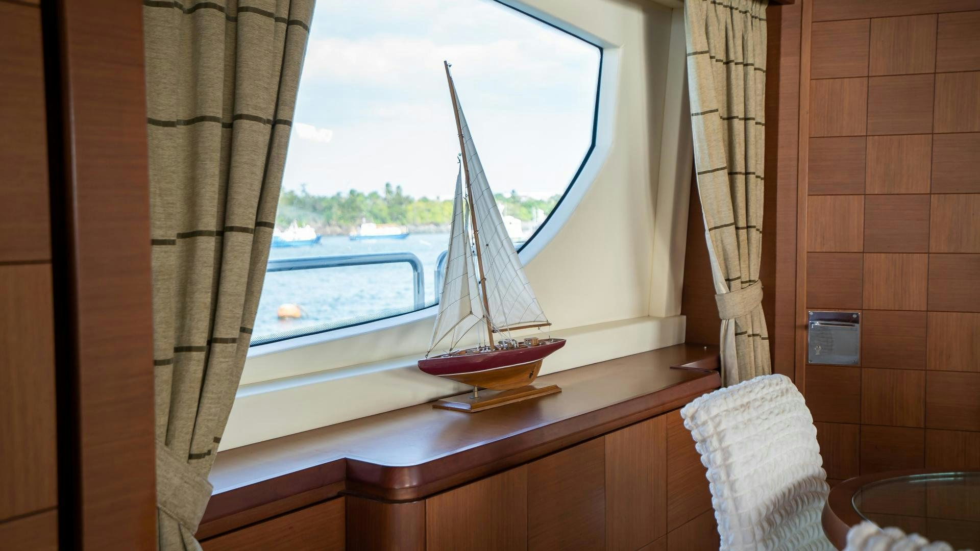 a window with a curtain and a table with a chair and a window aboard CAMY ED Yacht for Sale