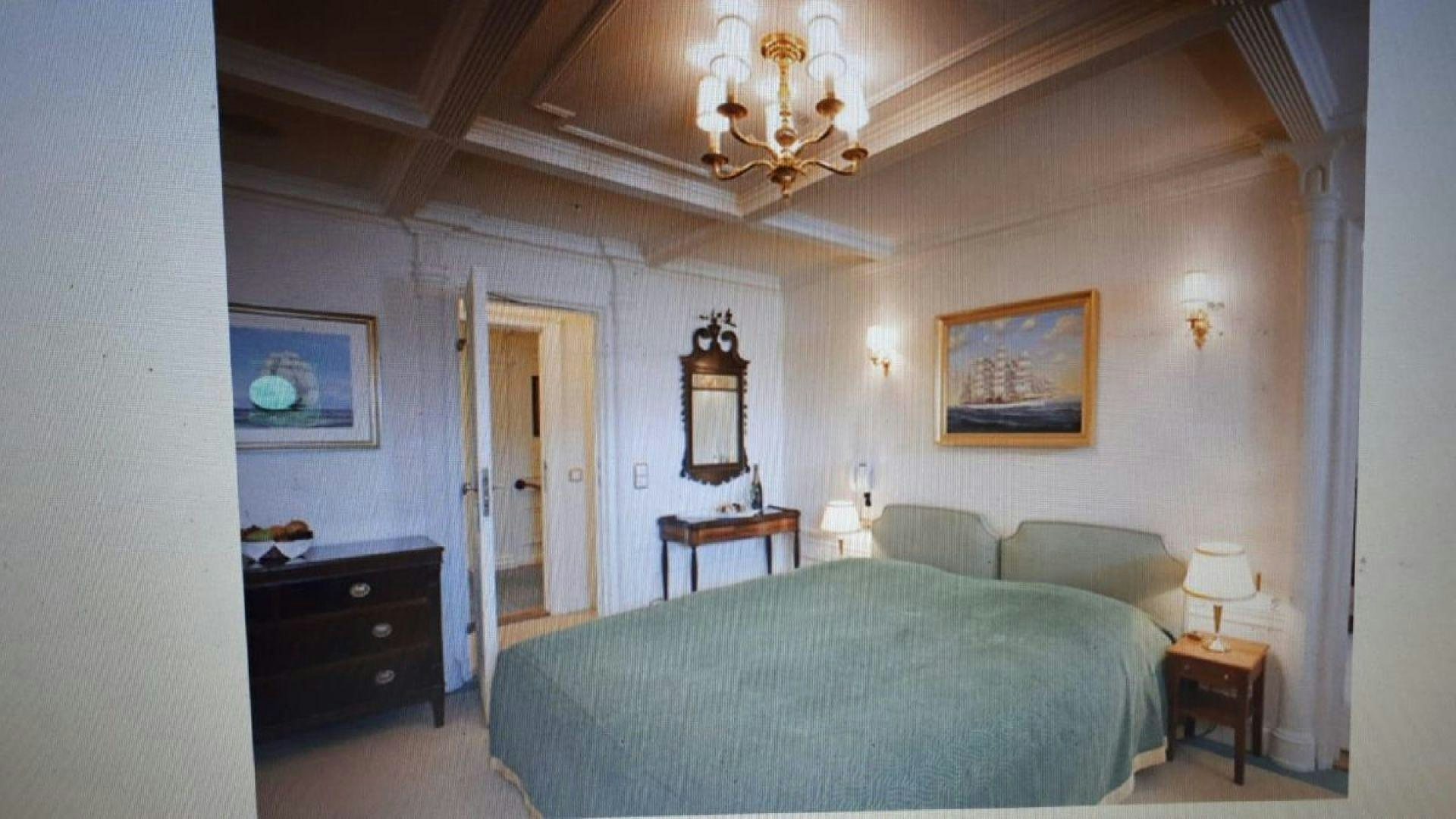 a bedroom with a bed and a chandelier aboard USS WILLIAMSBURG Yacht for Sale