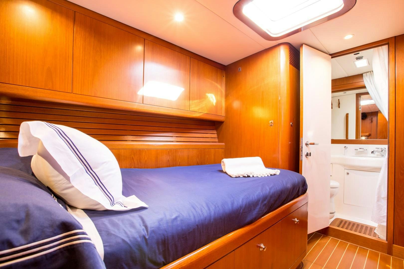 a bedroom with a bed and a wood cabinet aboard UMIKO Yacht for Sale