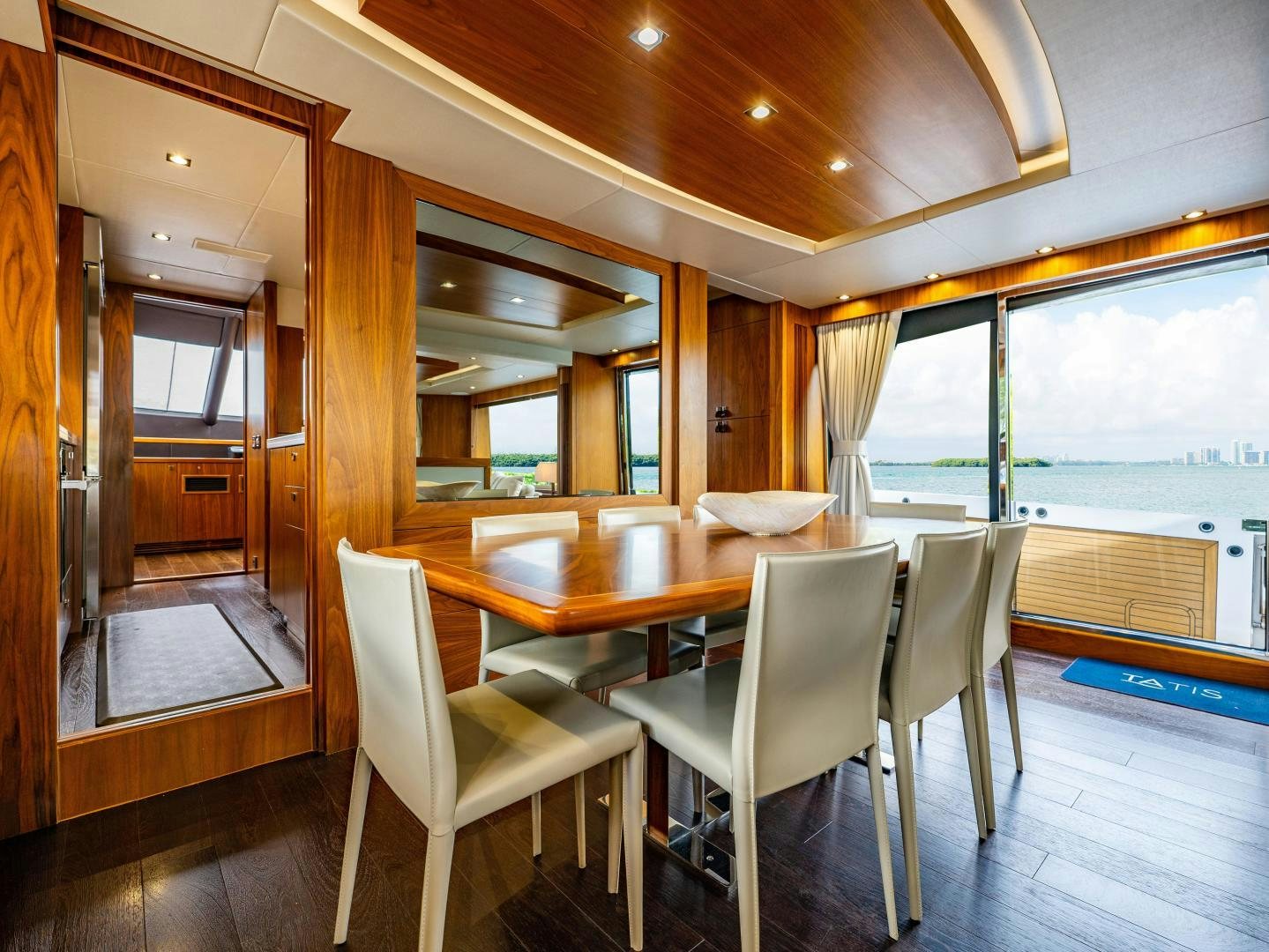 a dining table and chairs in a room with a view of the water aboard TATIS Yacht for Sale