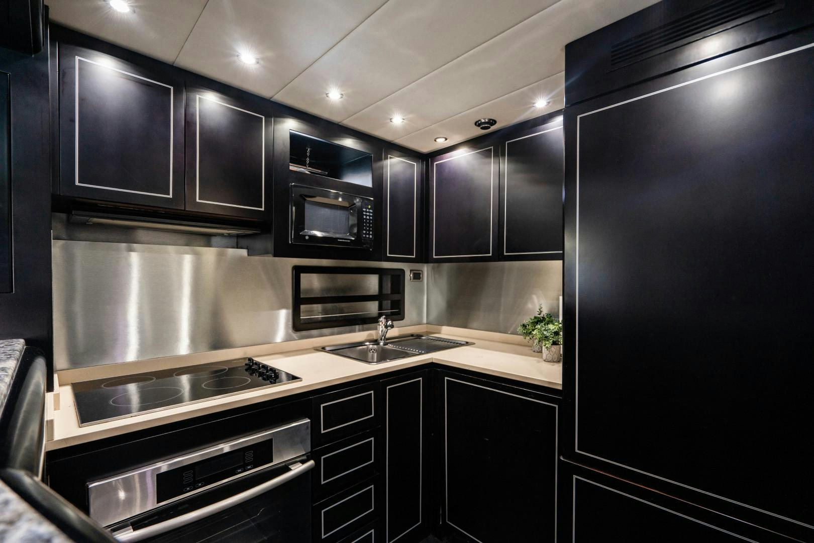 a kitchen with black cabinets aboard IV GIOCARE Yacht for Sale