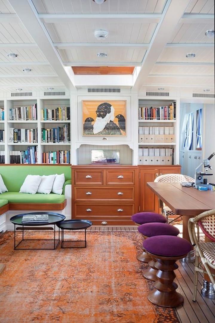 a room with a couch and a table and a bookcase aboard DARWIN Yacht for Sale