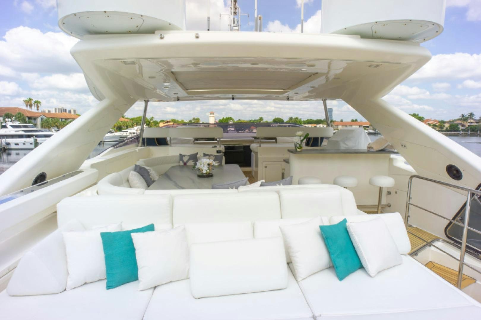 a large white lounge chair on a balcony with a large white building and blue sky aboard ADAR Yacht for Sale
