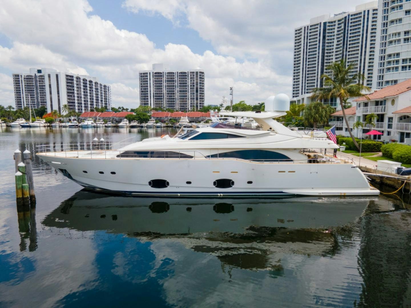 a white boat in a body of water with buildings in the background aboard ADAR Yacht for Sale