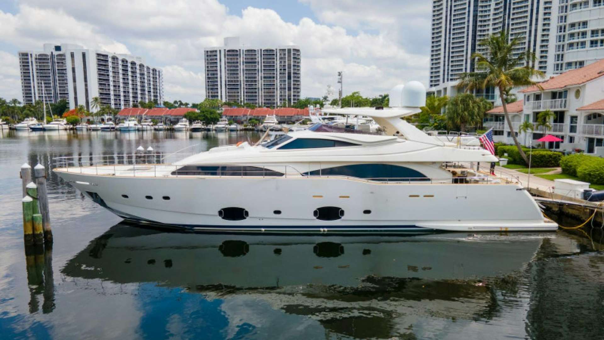 a white boat in a body of water with buildings in the background aboard ADAR Yacht for Sale