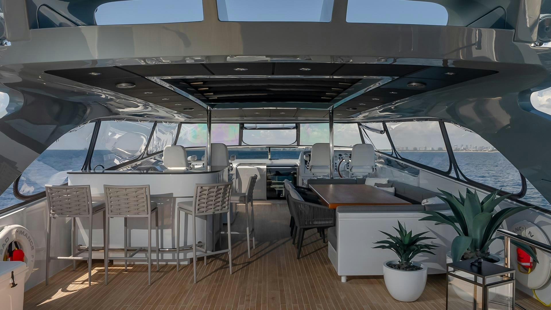 inside of a building with a table and chairs and plants aboard BAD ROMANCE IV Yacht for Sale