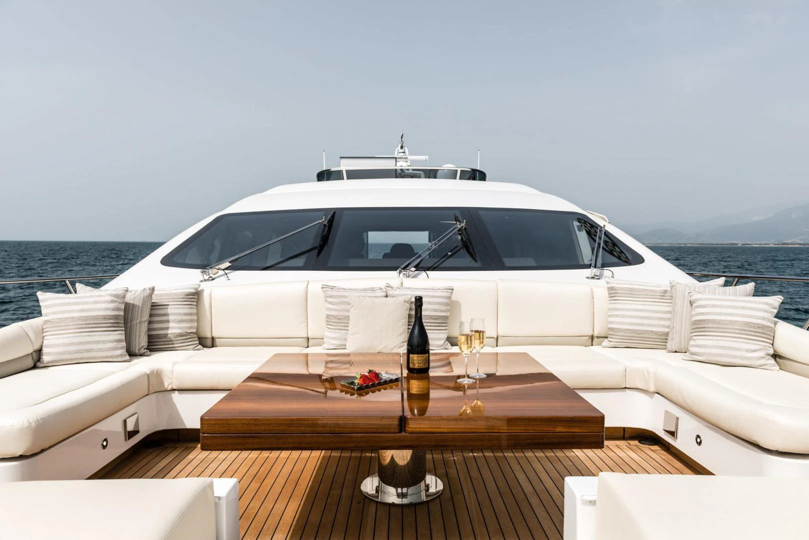 a white yacht with a glass of beer on a wooden table on a boat aboard WINGS SPREAD Yacht for Sale