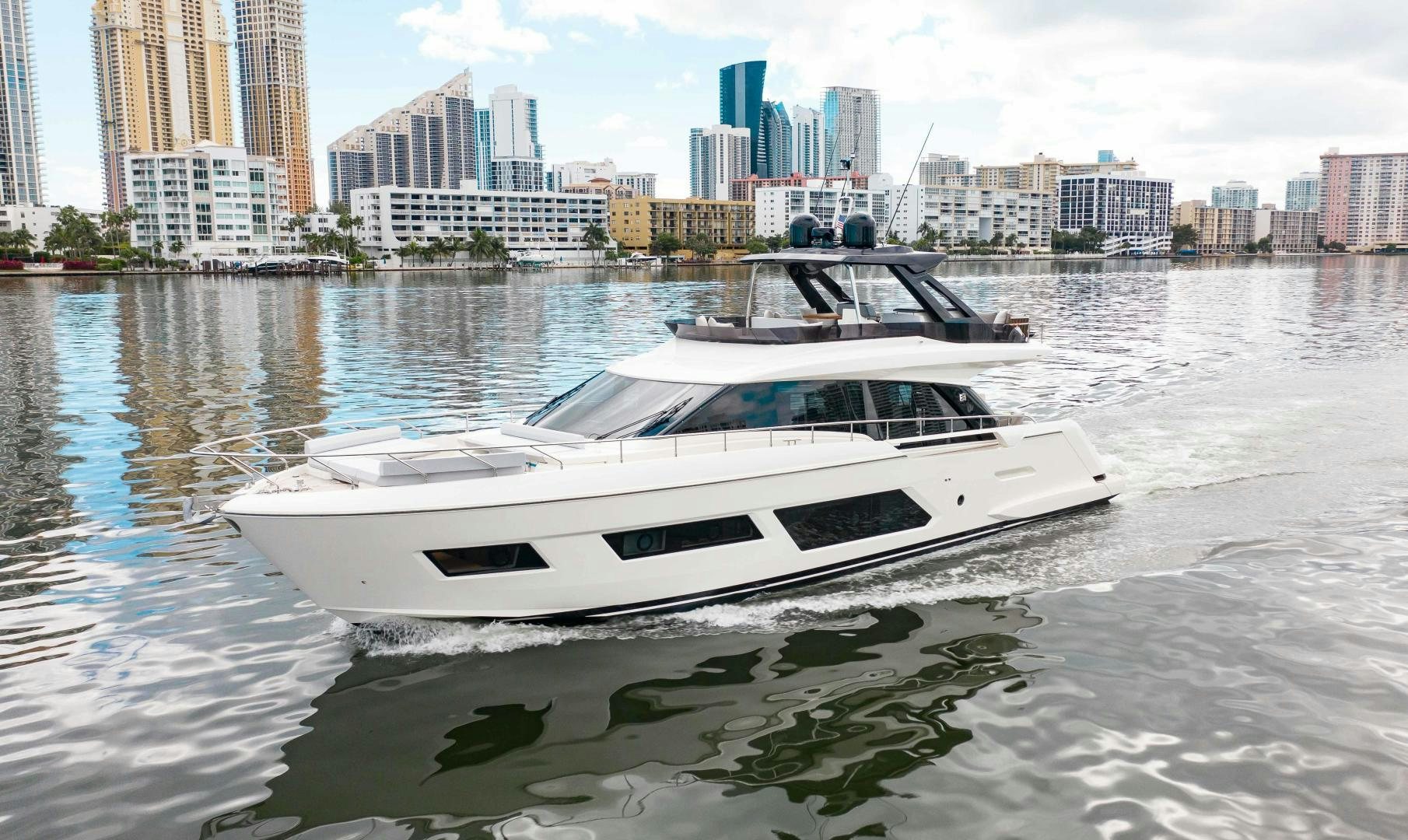 a white boat in a body of water with buildings in the background aboard Ferretti 670 Yacht for Sale