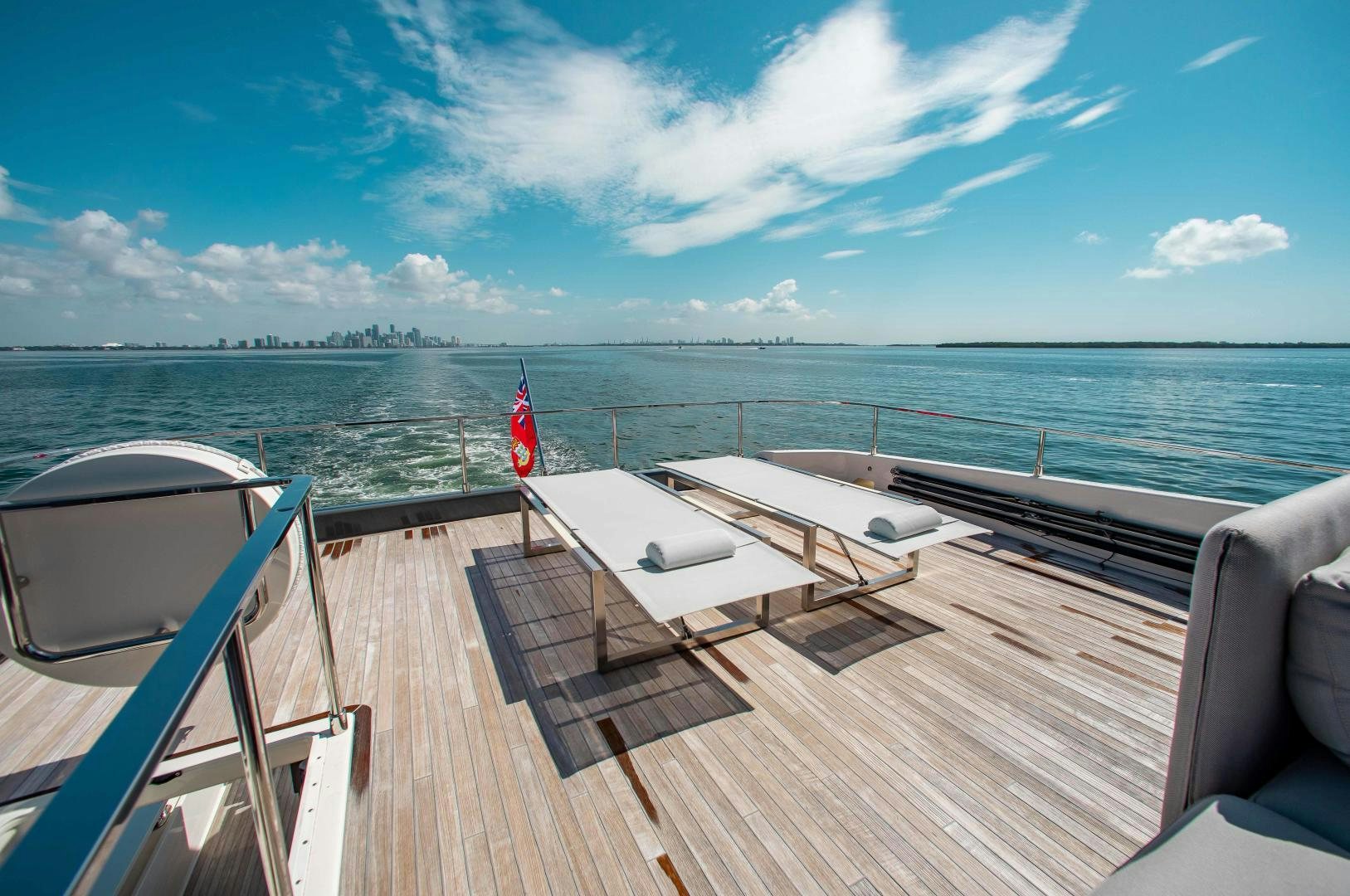 a deck with chairs and a flag on it by the water aboard CRAZY Yacht for Sale