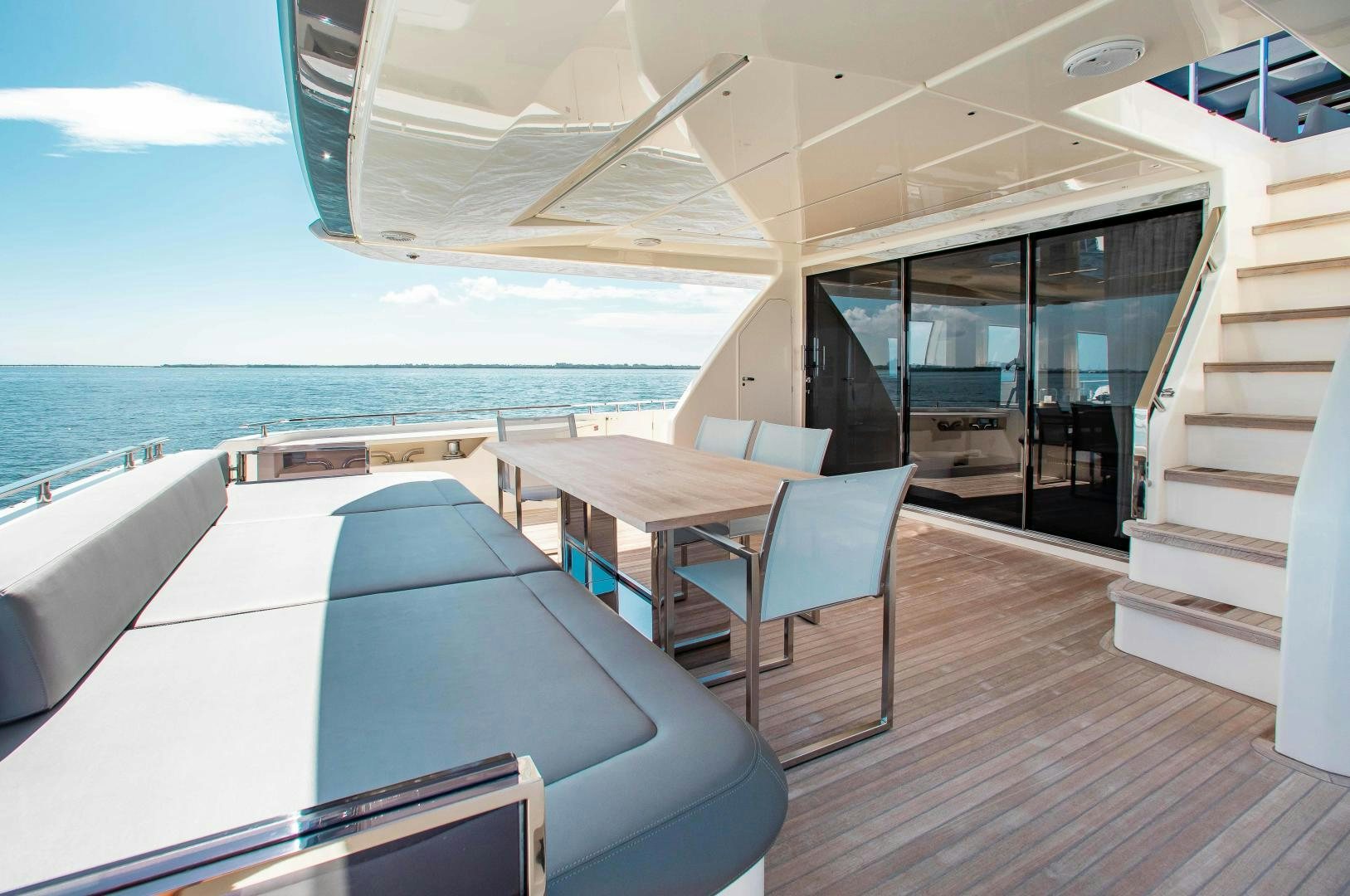 a room with a table and chairs on a deck overlooking the ocean aboard CRAZY Yacht for Sale