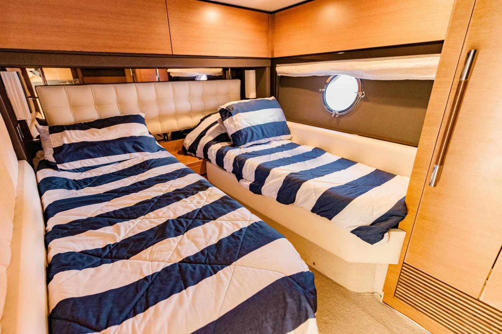 a bed with blue and white striped sheets aboard Azimut 70 Yacht for Sale