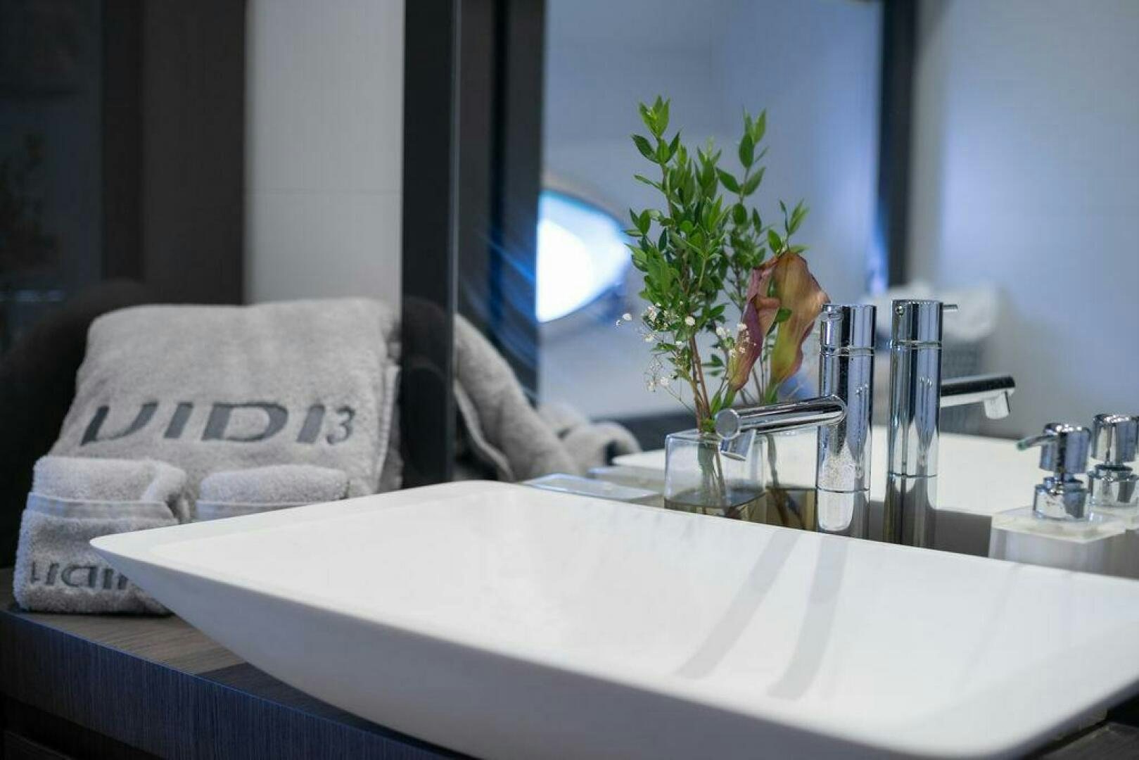 a white bed with a plant in a glass case aboard VIDI Yacht for Sale