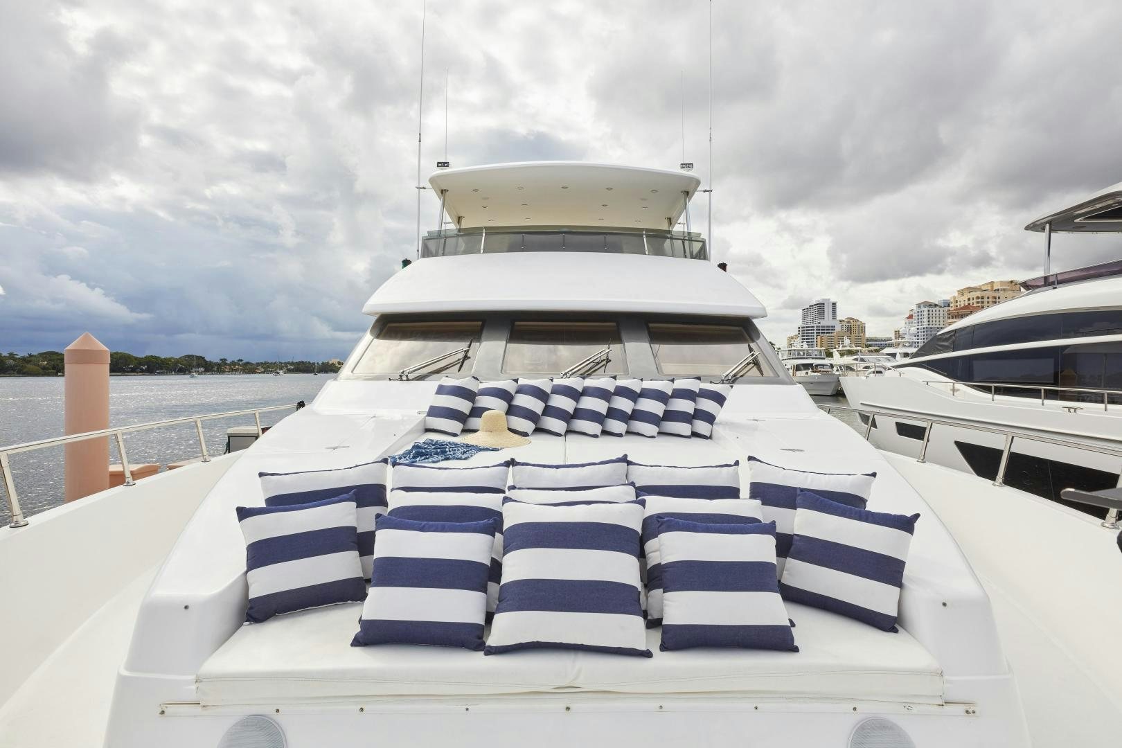 a large white boat with blue and white striped seats on a cloudy day aboard GRACE Yacht for Sale