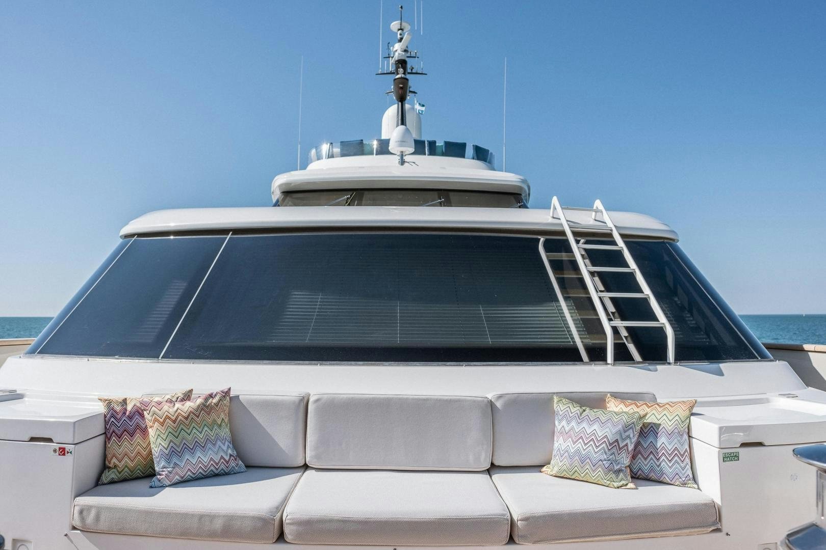 a white boat with a white roof and a white and blue striped pillow on a white couch with aboard AKAR XIII Yacht for Sale