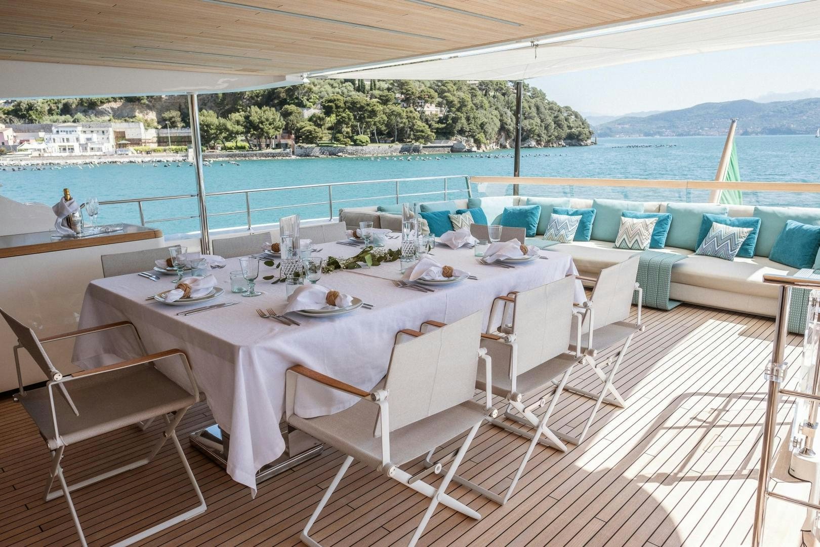 a table set for a meal on a balcony overlooking a beach aboard AKAR XIII Yacht for Sale