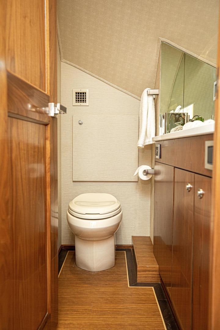 a bathroom with a toilet and wooden cabinets aboard SPECULATOR Yacht for Sale