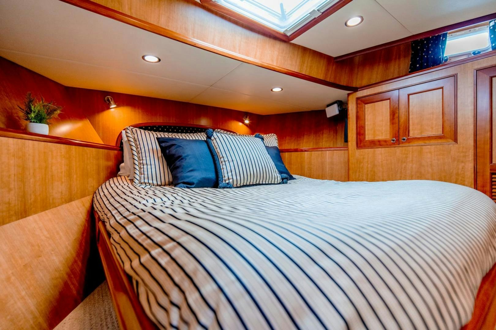 a bed with blue and white striped sheets aboard HONORE Yacht for Sale