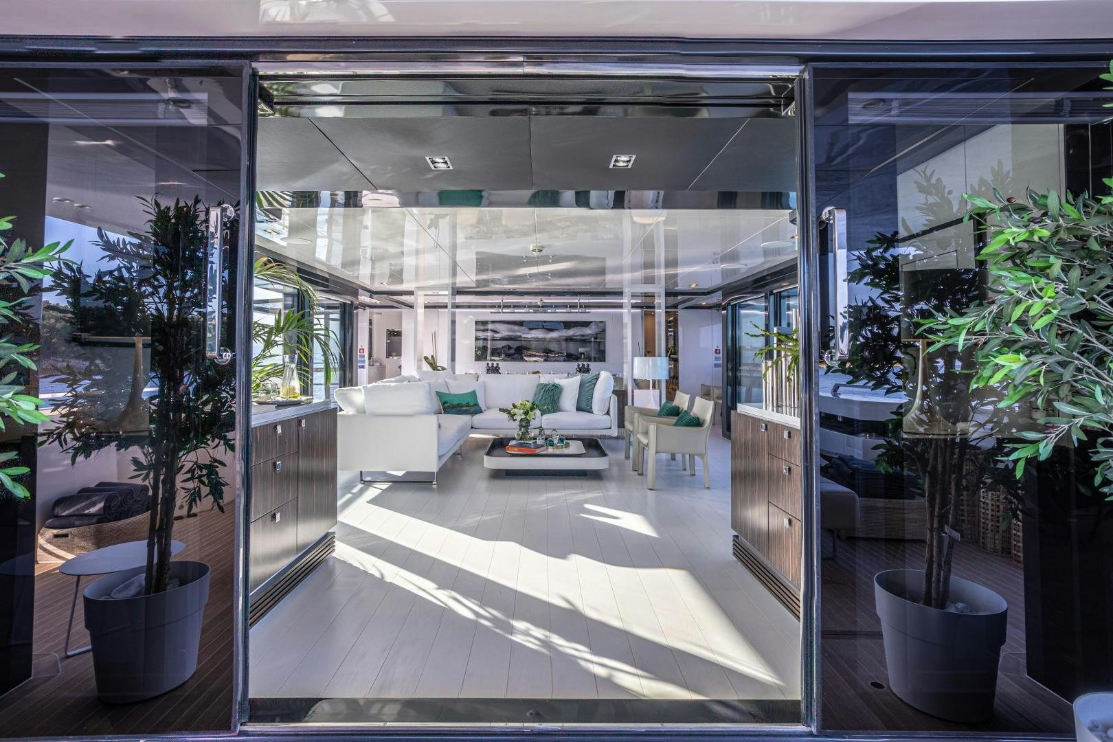 a room with a white couch and plants aboard M Yacht for Sale