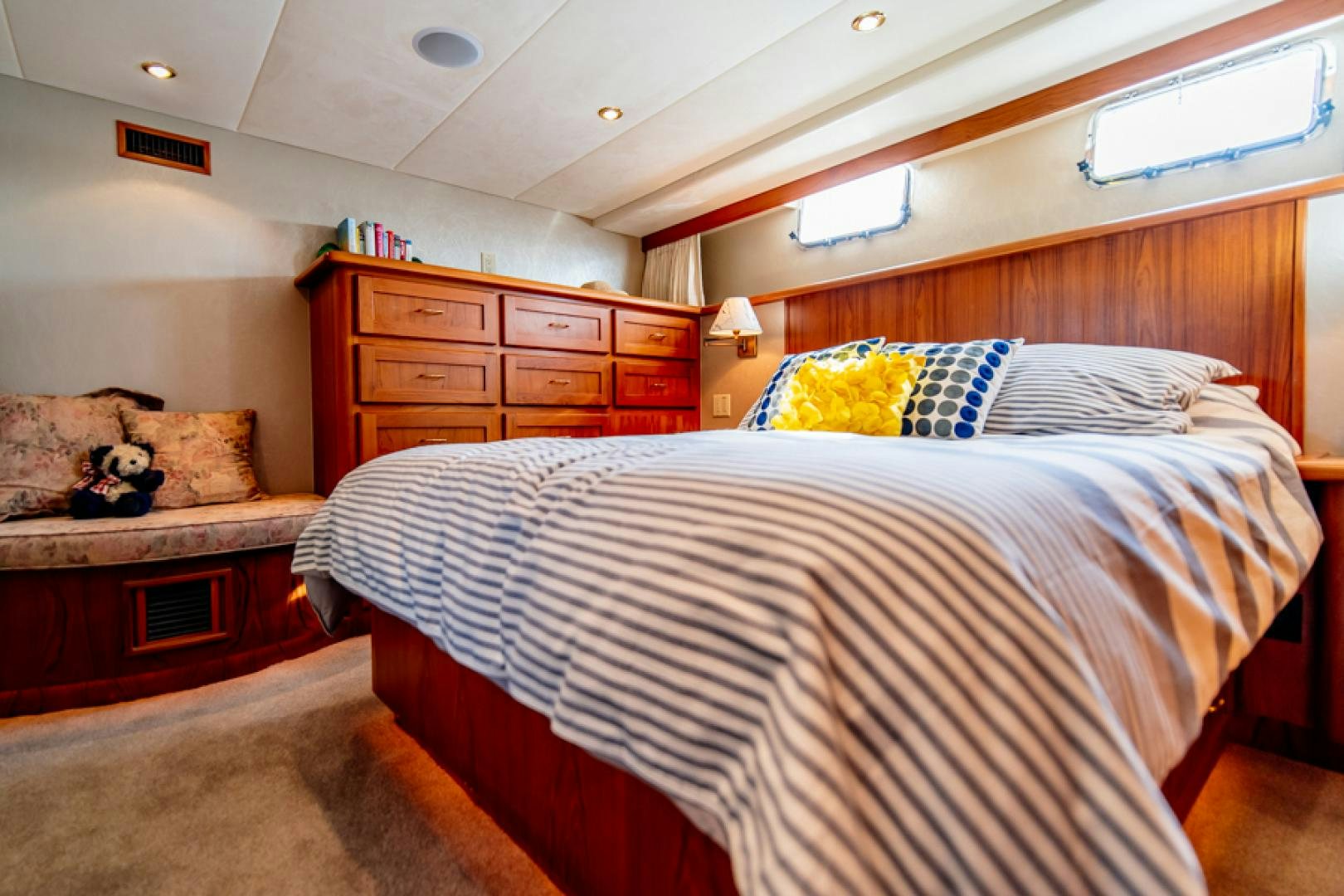 a bedroom with a bed and a dresser aboard the happy boat Yacht for Sale