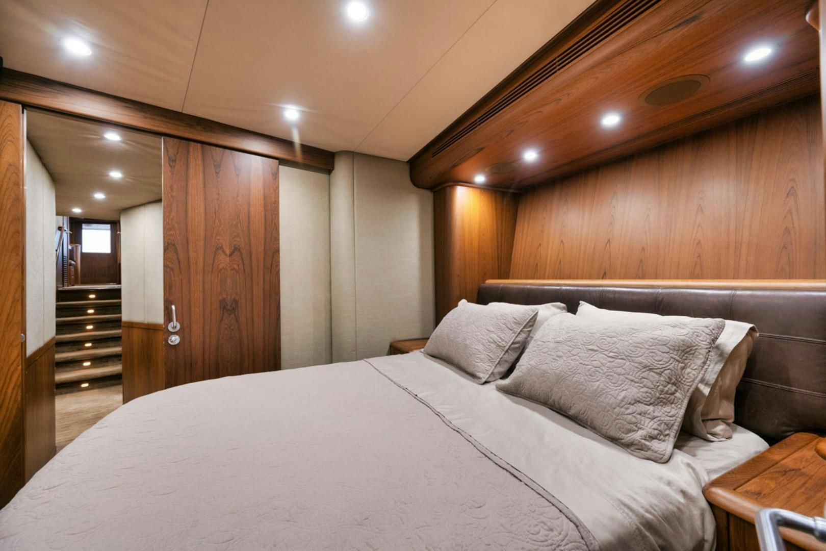a bed with a white sheet and a wooden door aboard SIR REEL Yacht for Sale