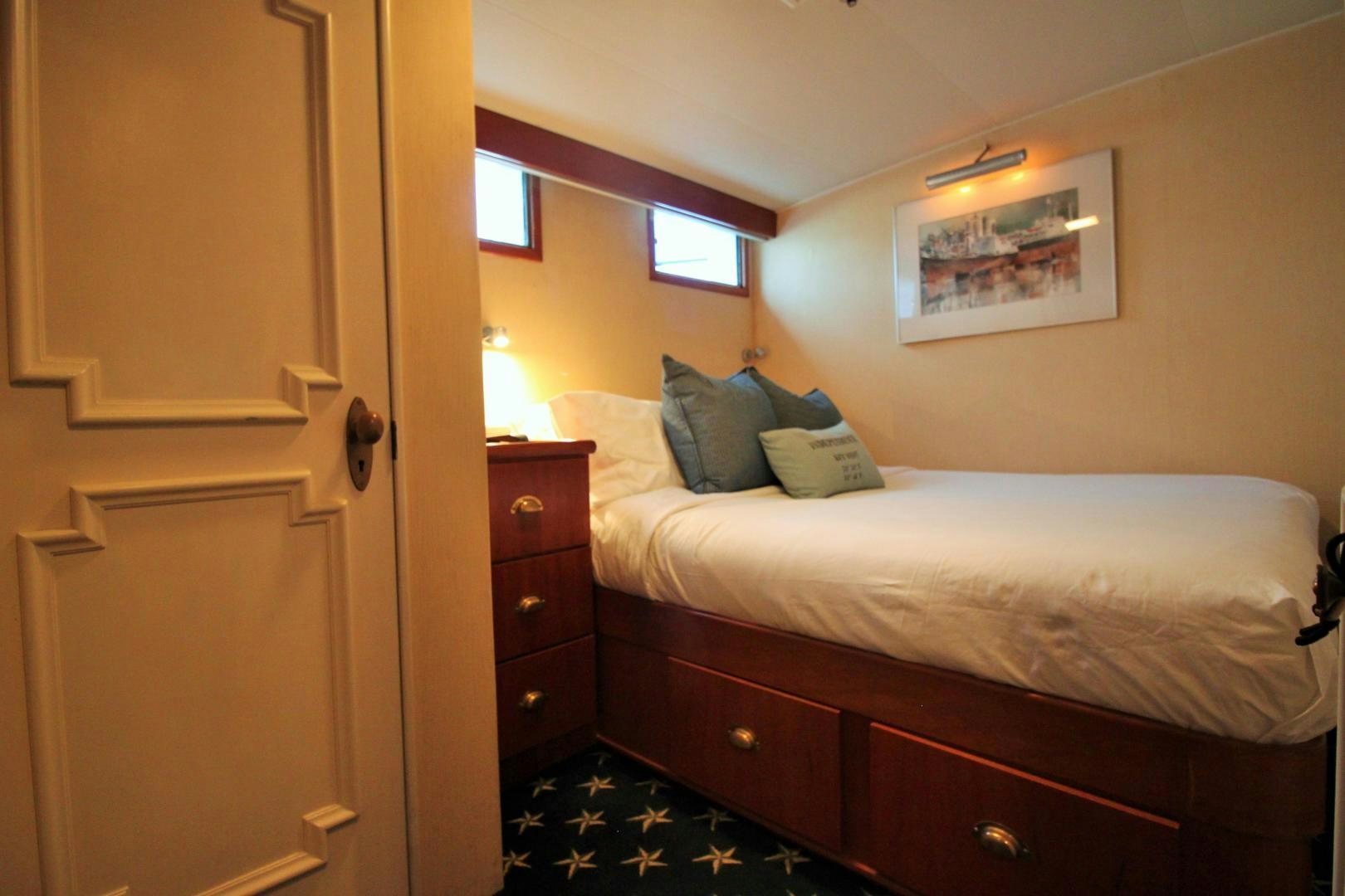 a bedroom with a bed and a dresser aboard Independence Yacht for Sale
