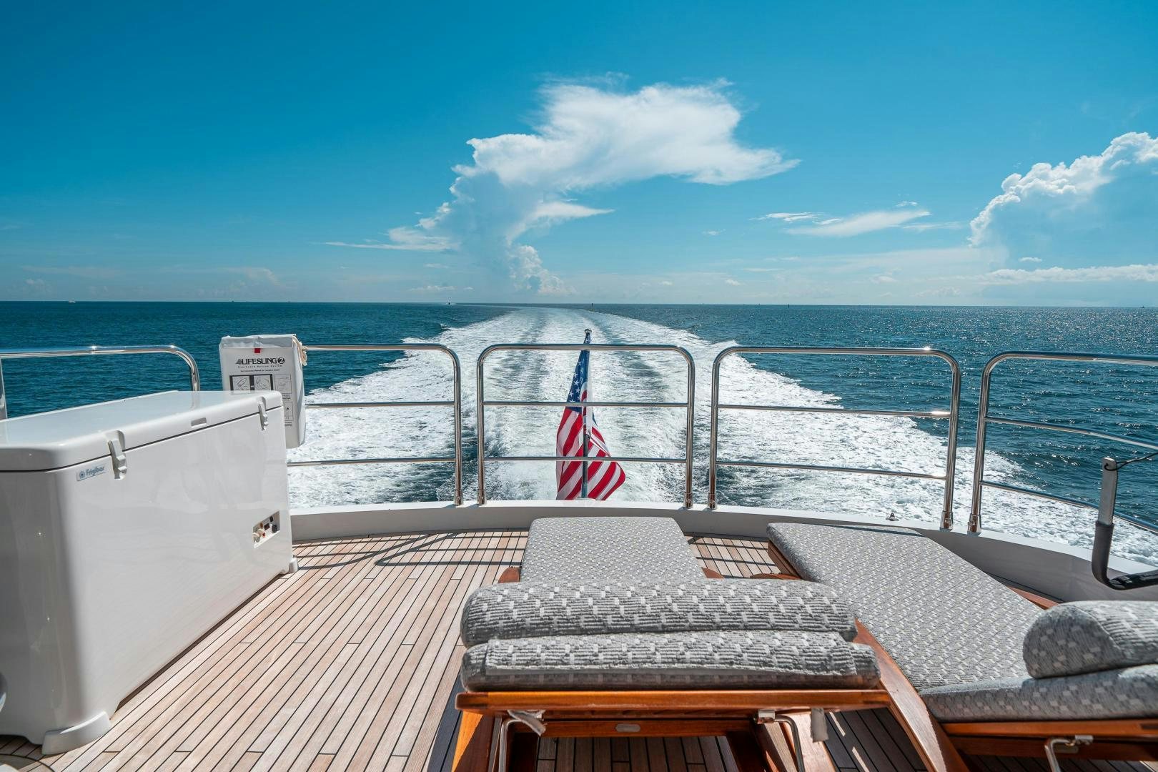 a deck with a railing and a flag on it aboard Life for Sale Yacht for Sale