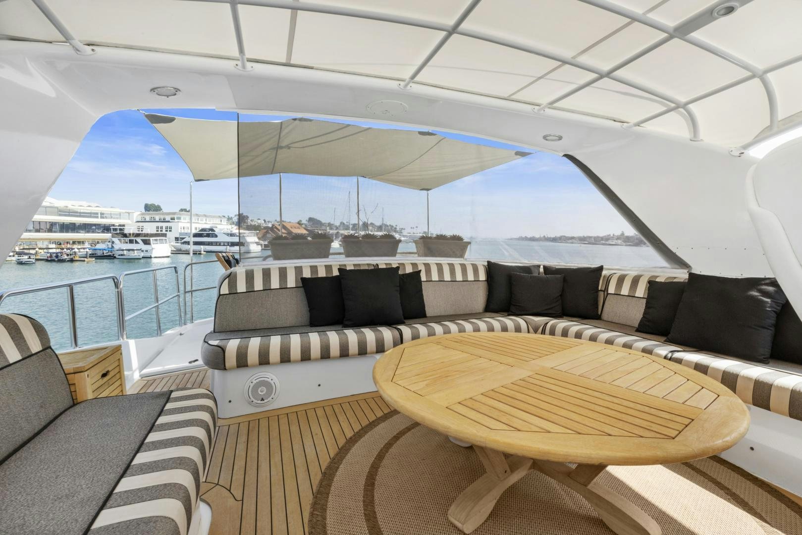 a large lounge area with a large body of water and boats in the background aboard RILASSARI Yacht for Sale