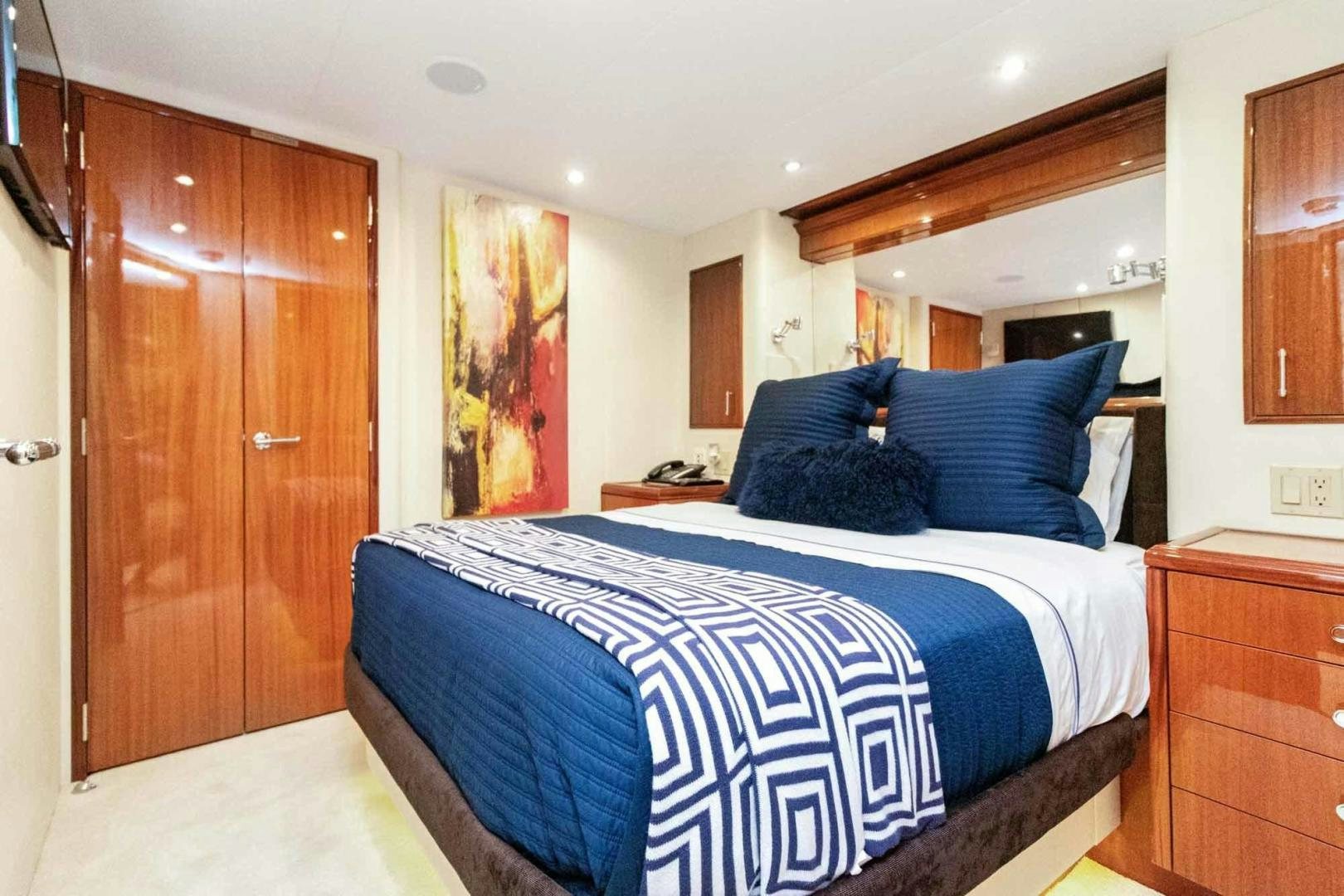 a bedroom with a bed and wooden cabinets aboard SEMPER FI Yacht for Sale