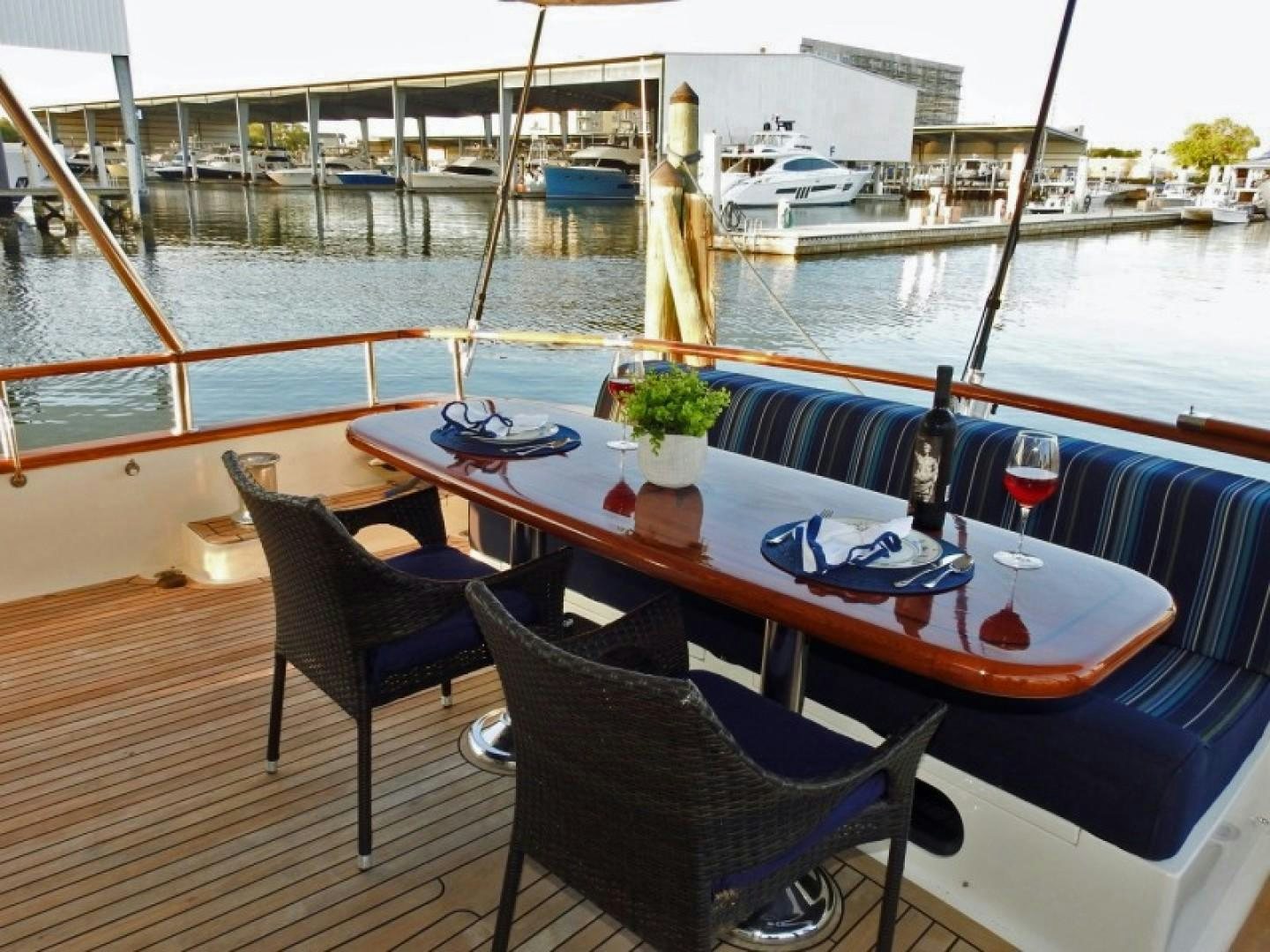a table with chairs and bottles on it by a body of water aboard AGAVE Yacht for Sale