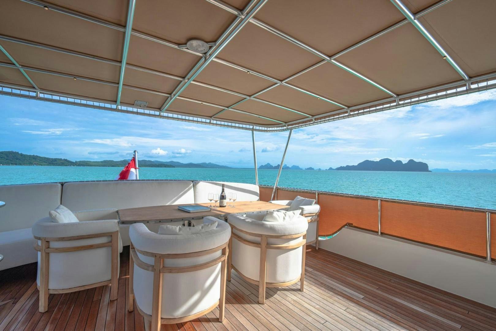 a table and chairs on a deck overlooking the ocean aboard DOUBLEYOU Yacht for Sale