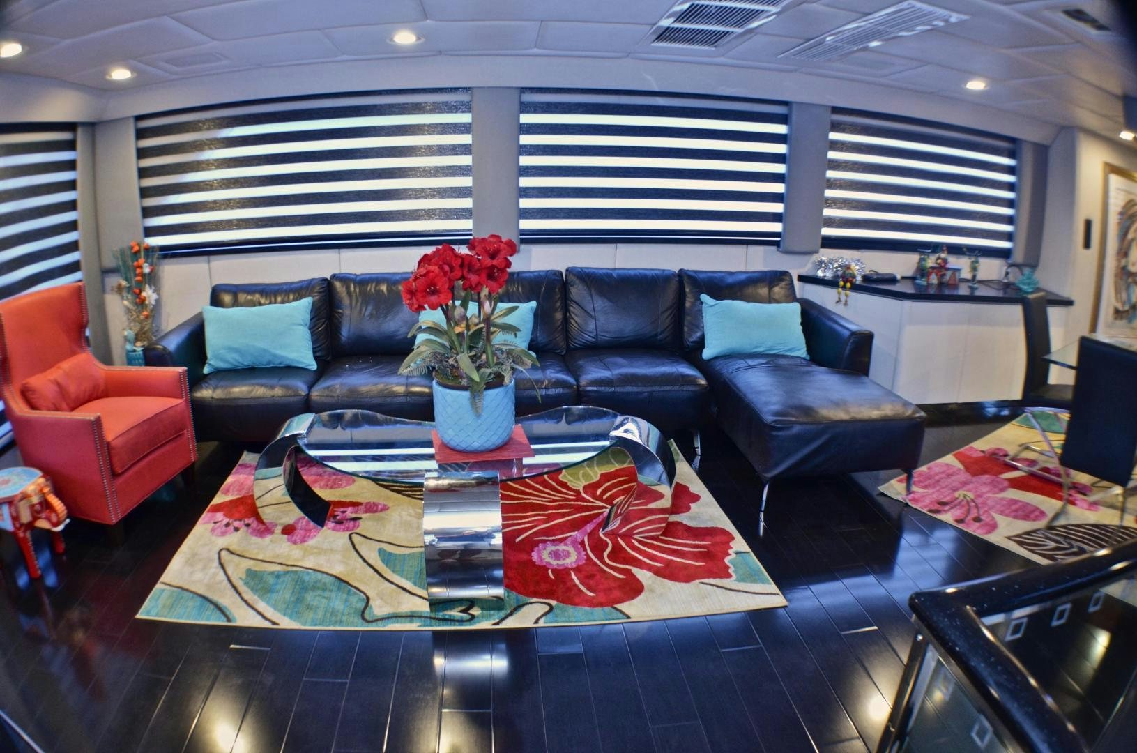 a living room with a large glass coffee table and a large red flower on the coffee table aboard AUDACITY Yacht for Sale