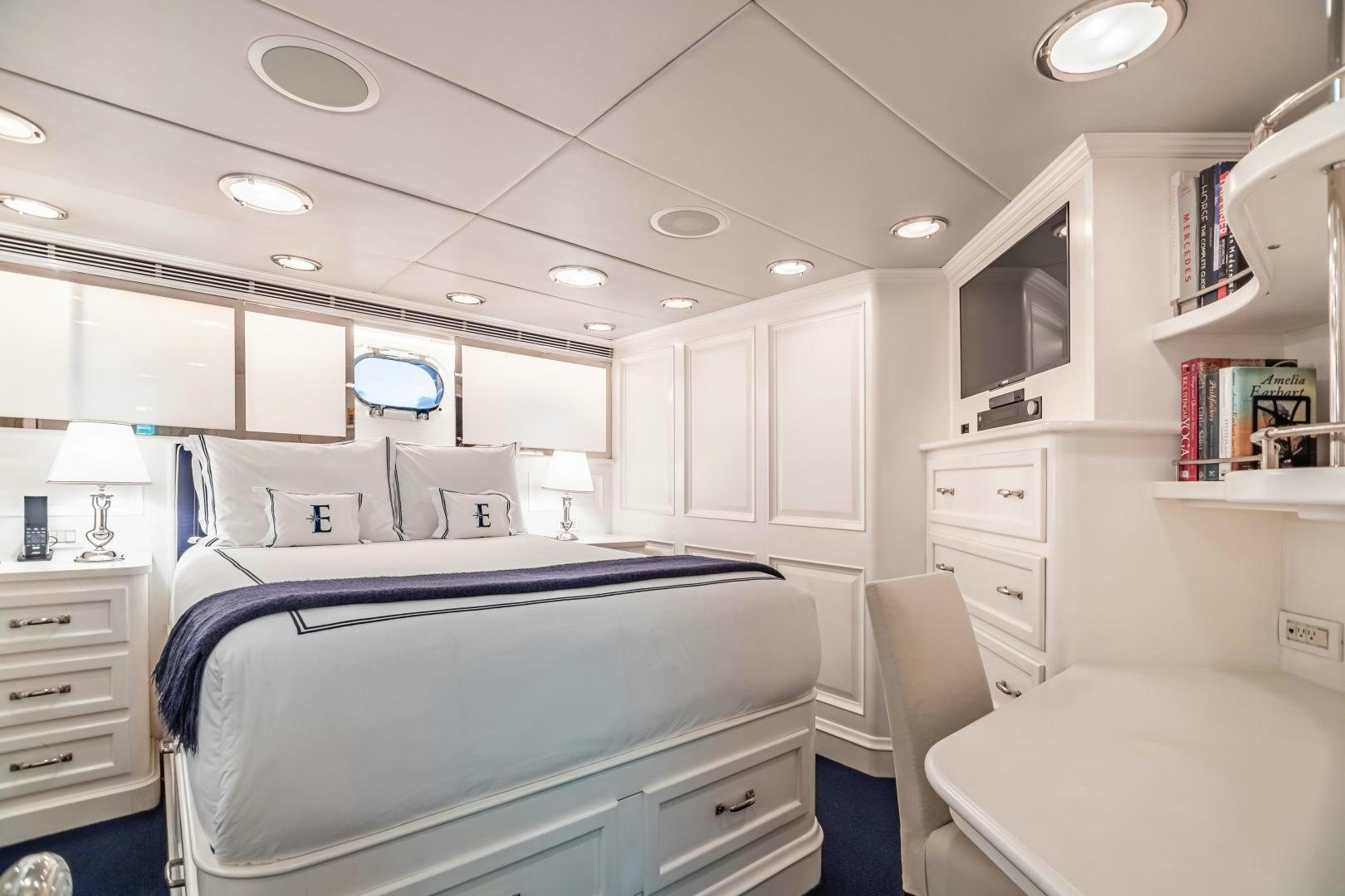 a bedroom with a bed and a desk aboard EXPLORA Yacht for Sale