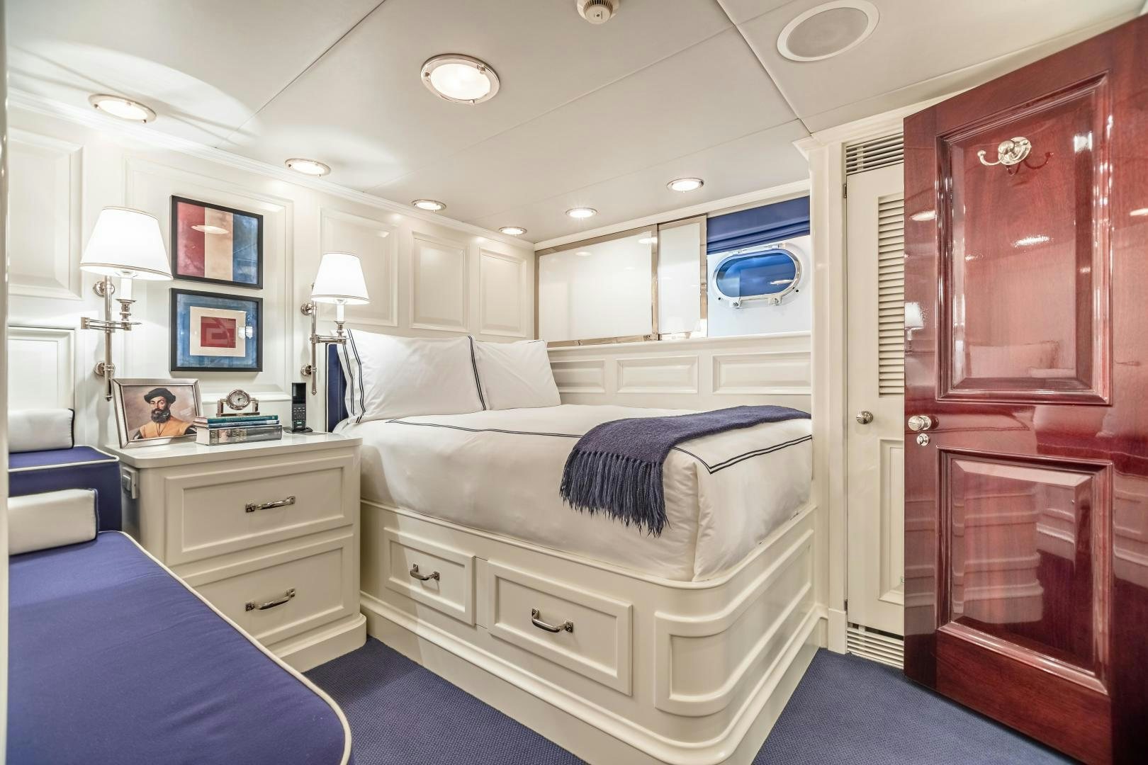 a bedroom with a bed and a dresser aboard EXPLORA Yacht for Sale