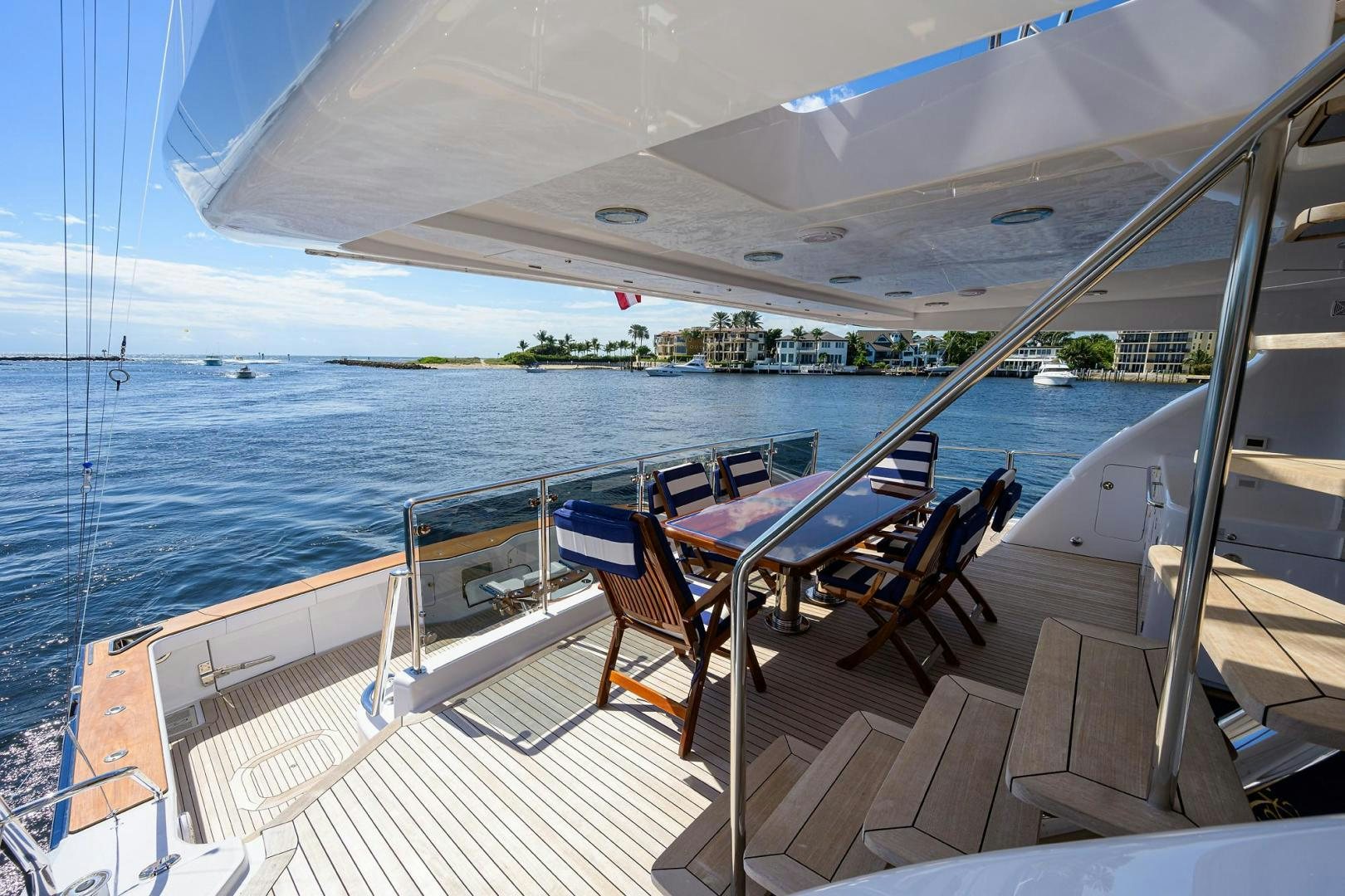 a deck with chairs and tables on it by a body of water aboard THE CROWN ROYAL Yacht for Sale