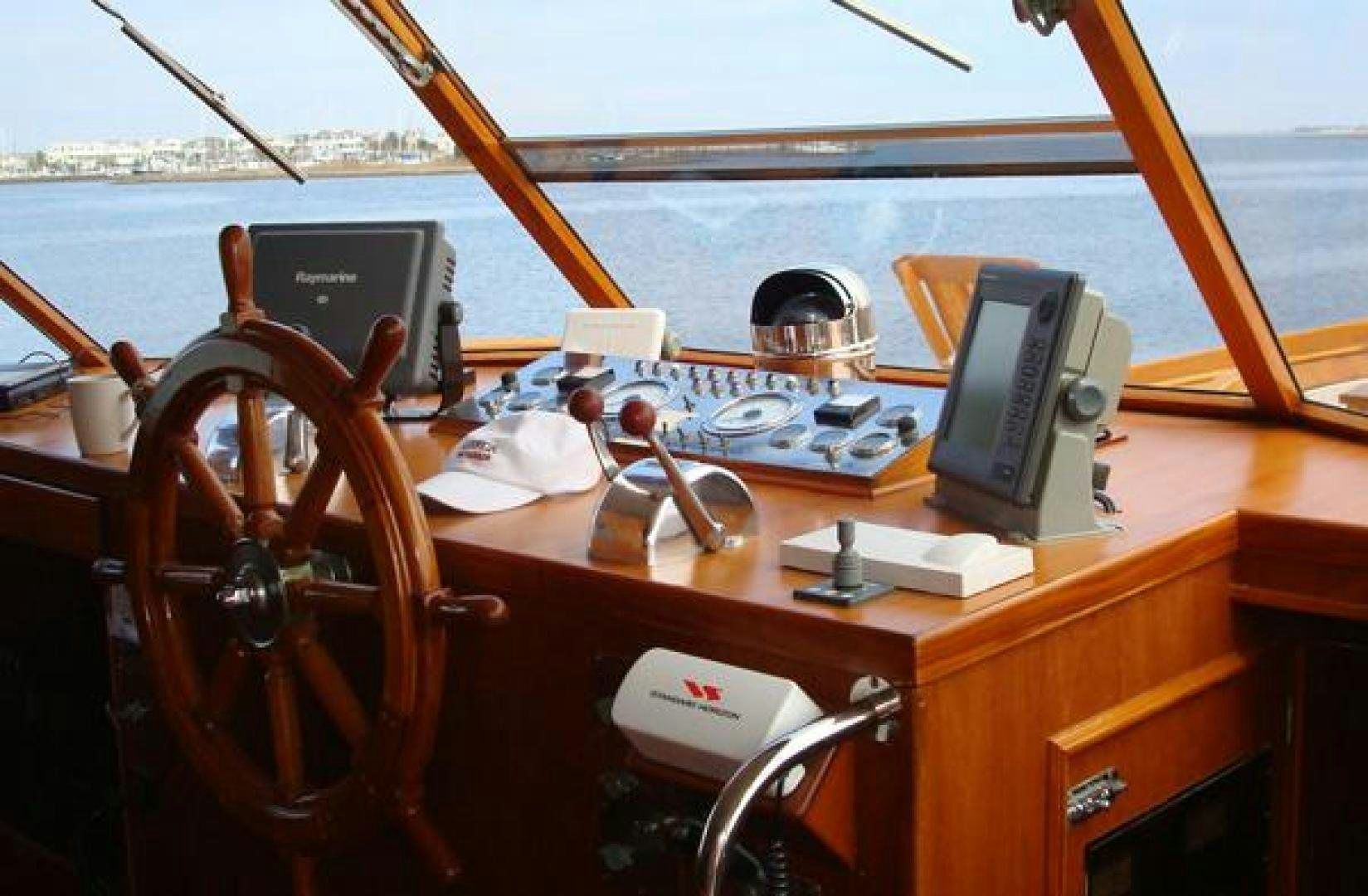 a wooden table with a computer and other objects on it aboard AMERICA Yacht for Sale