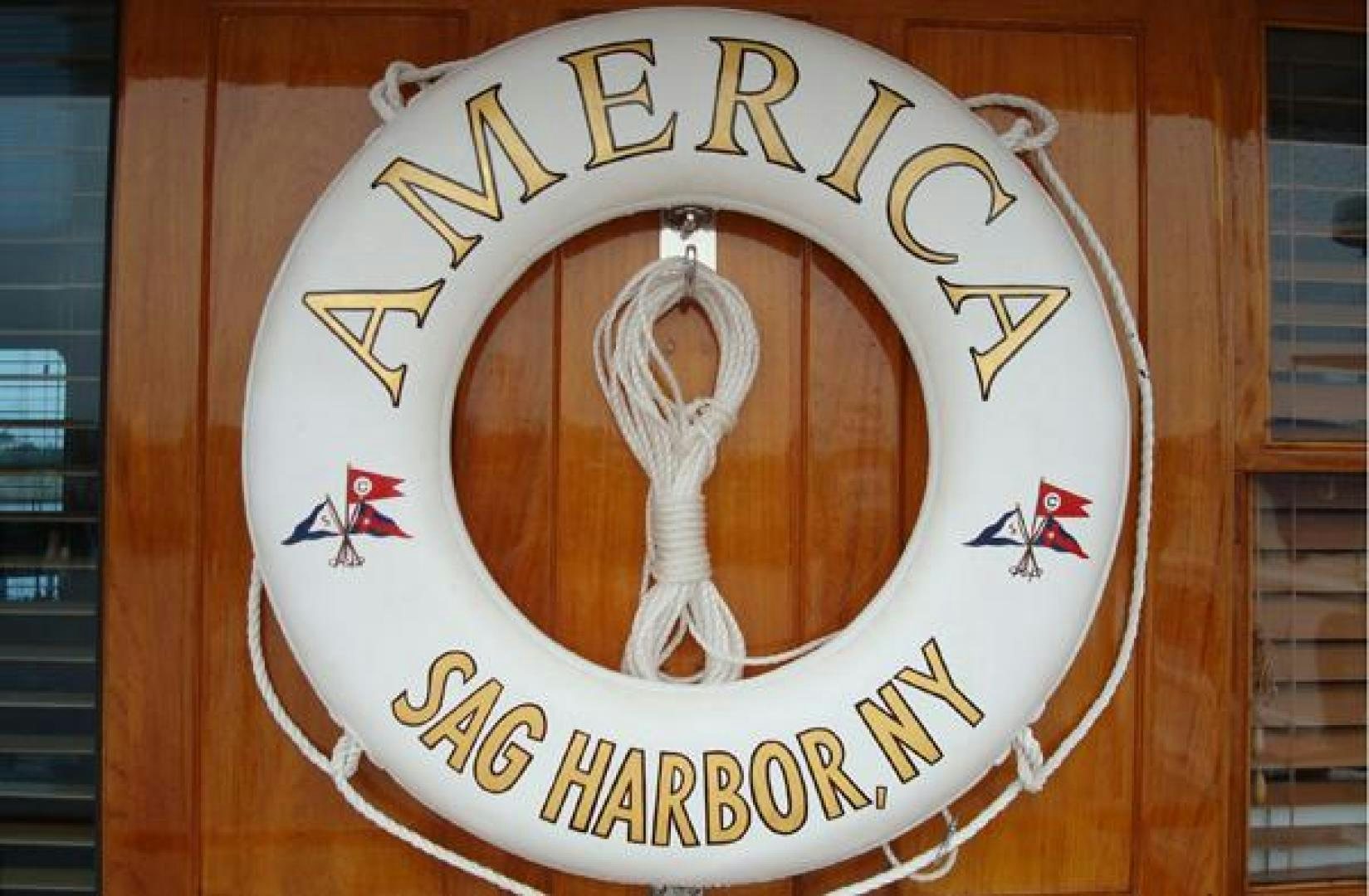 a gold and white logo aboard AMERICA Yacht for Sale