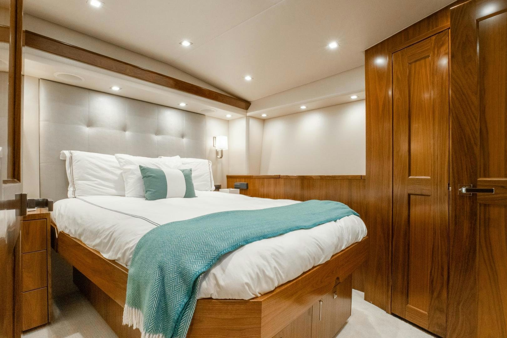 a bedroom with a bed and a wood door aboard POMPINA Yacht for Sale