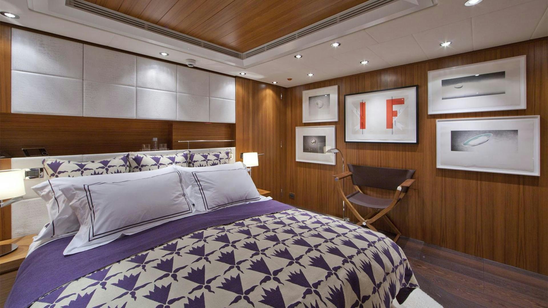 a bed with a blue and white comforter and a chair in a room with wood walls and aboard SNOWBIRD Yacht for Sale