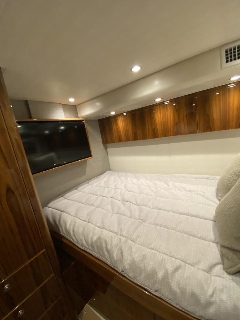a bed with a television on the wall aboard Make It Happen Yacht for Sale