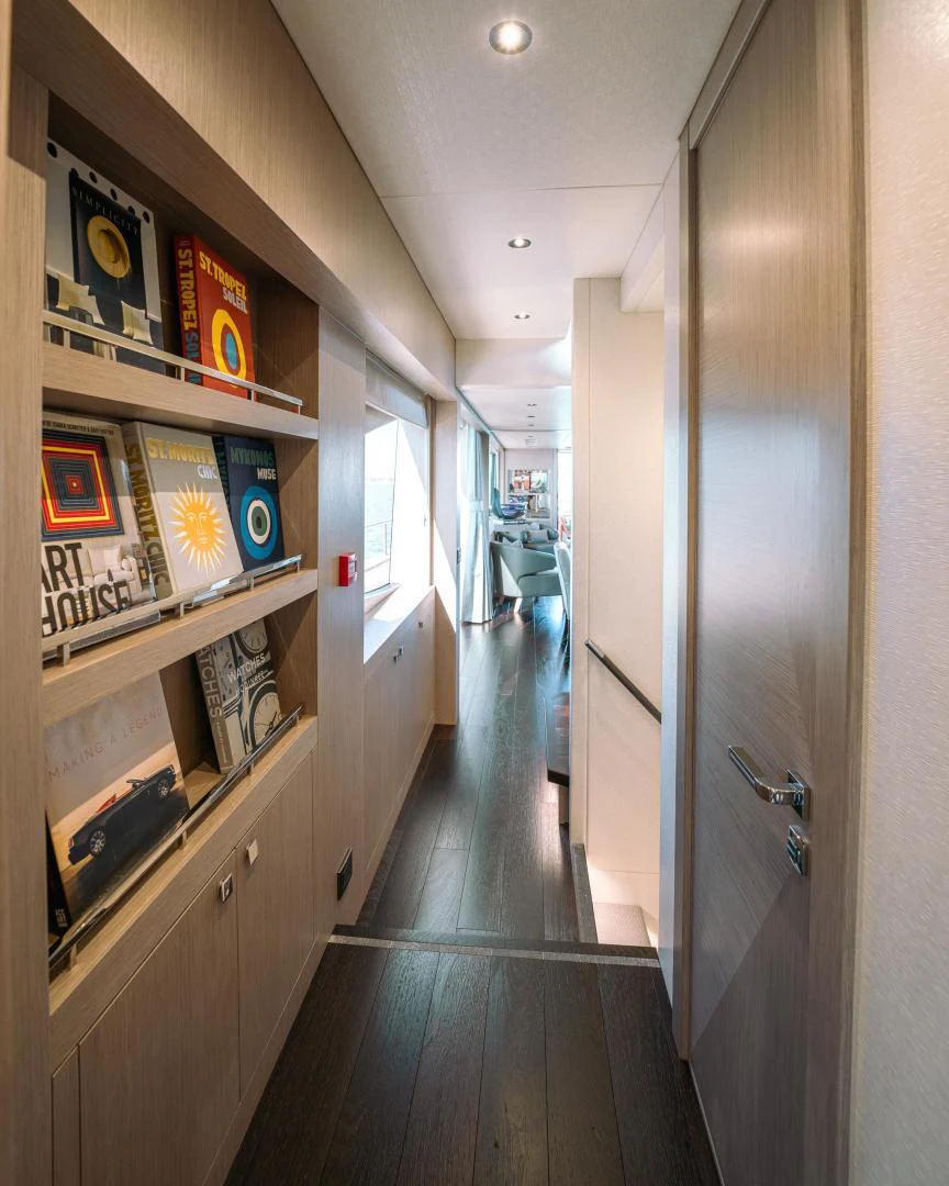 a hallway with shelves and books aboard EOS Yacht for Sale
