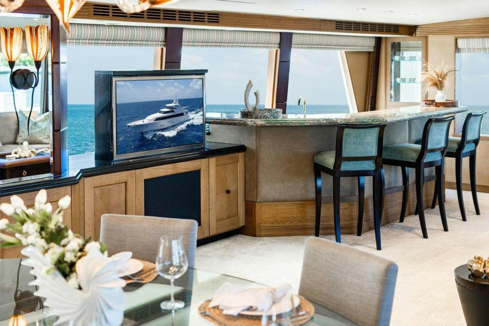 a room with a table chairs and a television aboard NORTH COAST 120 Yacht for Sale