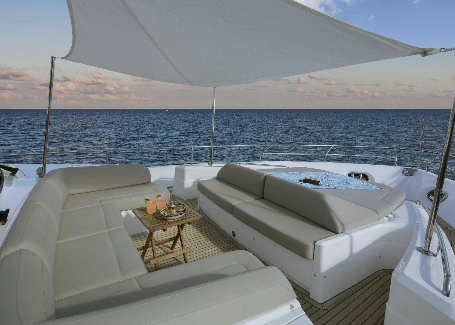 a lounge chair and a table on a beach aboard HOT PURSUIT Yacht for Sale
